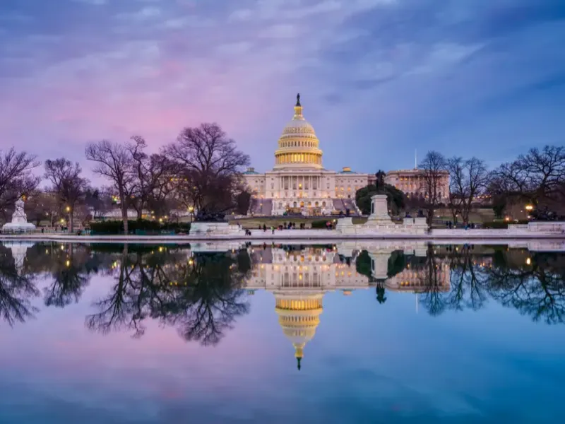 Washington DC US Capitol Building illuminated at twilight reflected in the Capitol Reflecting Pool under a purple and pink sky