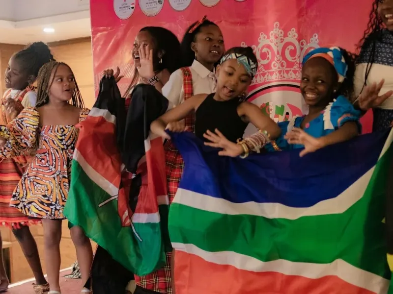 Young people joyfully celebrating African American heritage and freedom with flags at a Juneteenth cultural celebration