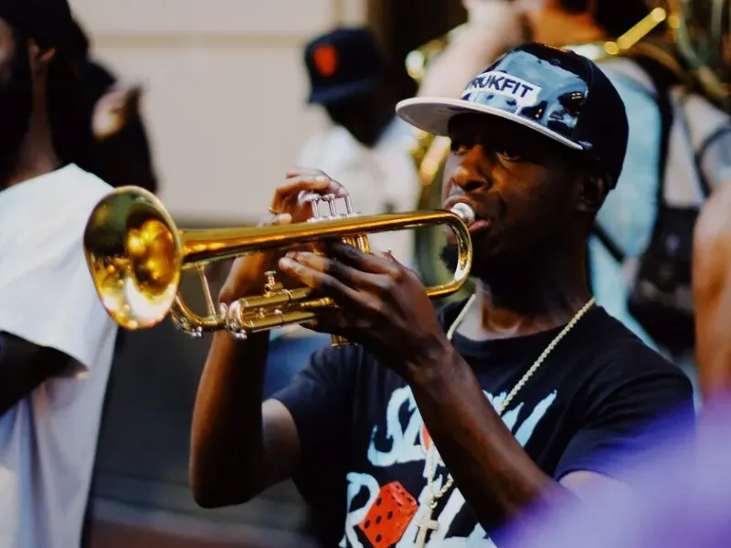 A New Orleans brass band trumpeter performing on the street with a sousaphone behind him