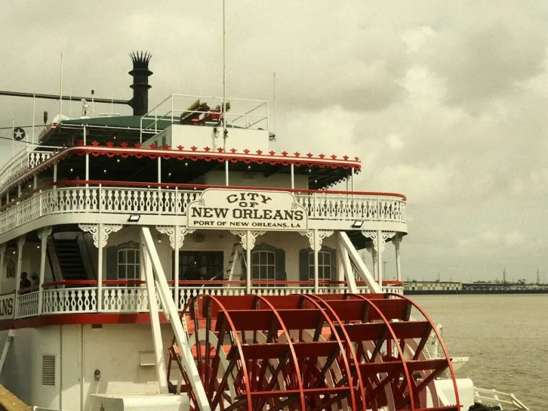 A red paddlewheel steamboat docked on the Mississippi River in New Orleans