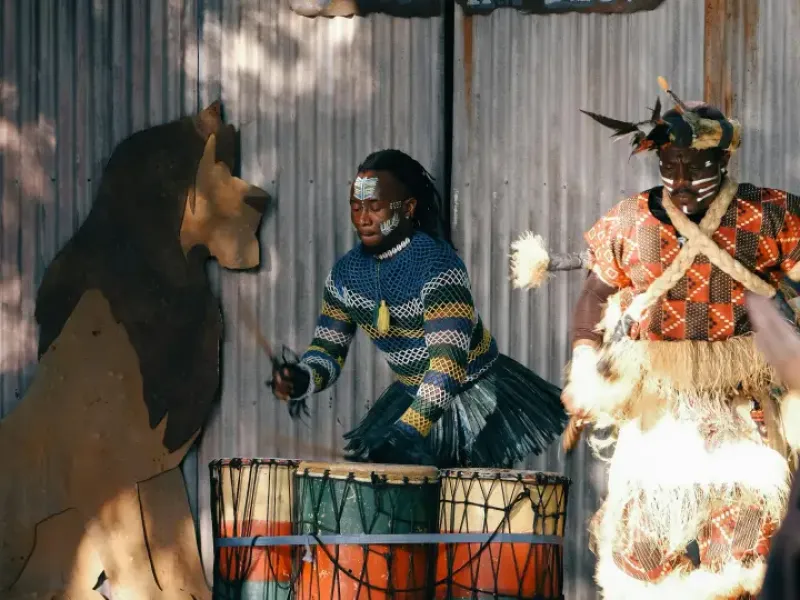 Two performers in traditional African costumes and face paint play drums on stage at an Orlando; FL cultural show.