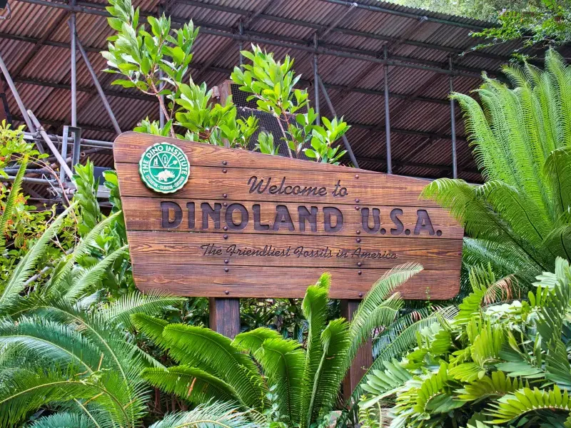 Wooden welcome sign for Dinoland U.S.A. at Disney's Animal Kingdom in Orlando; FL; surrounded by lush tropical ferns.