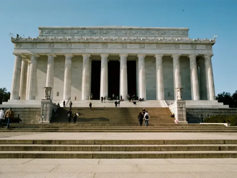 Visitors climbing the broad stone steps of the Lincoln Memorial in Washington; DC on a clear sunny day.