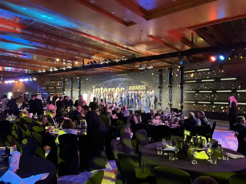 Crowd of attendees at the Intersec Awards gala dinner; with award winners gathered on a darkly lit stage.