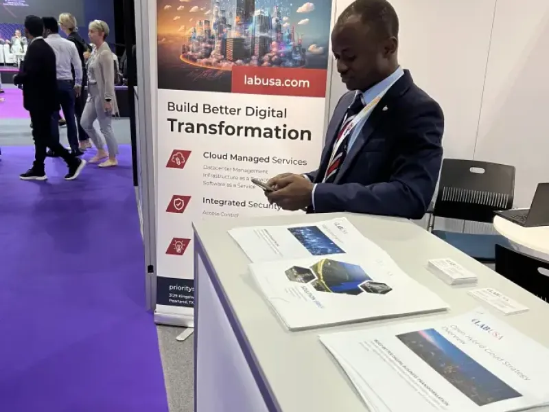 LABUSA representative in a dark suit at the Intersec conference booth beside a Build Better Digital Transformation banner promoting Cloud Managed Services and Integrated Security with brochures and a bowl of branded candy on the counter as attendees walk past.