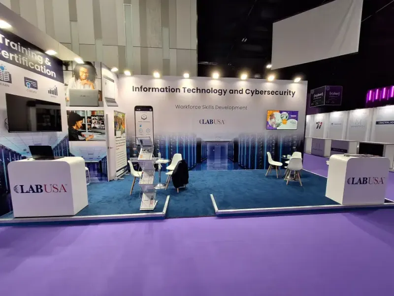 LABUSA exhibition booth at Intersec showcasing Information Technology and Cybersecurity Workforce Skills Development with Training & Certification signage brochure stands and a seating area on teal carpet.