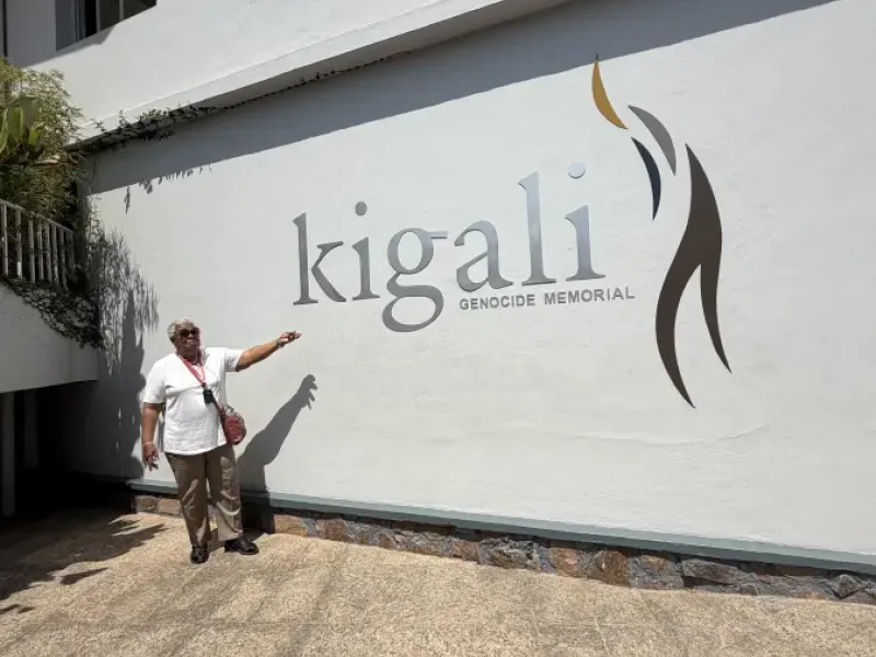 Visitor pointing to the Kigali Genocide Memorial sign on a white building wall in Kigali; Rwanda.