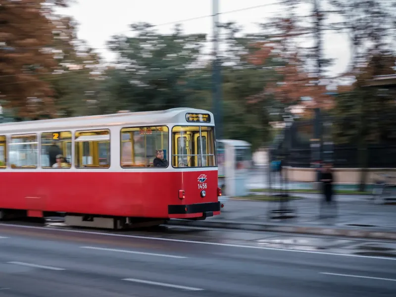 A red and white Vienna tram photographed in motion along a city street, the background blurred by the panning.