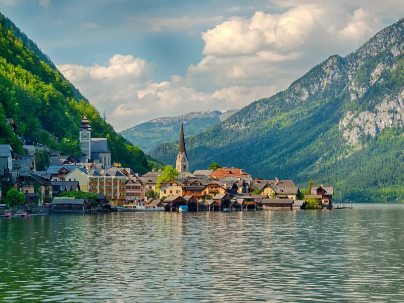The lakeside village of Hallstatt in Austria, its church spire and wooden boathouses below steep wooded slopes