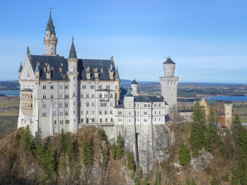 Neuschwanstein Castle in Bavaria, its pale towers rising from a wooded ridge above the Alpine foothills
