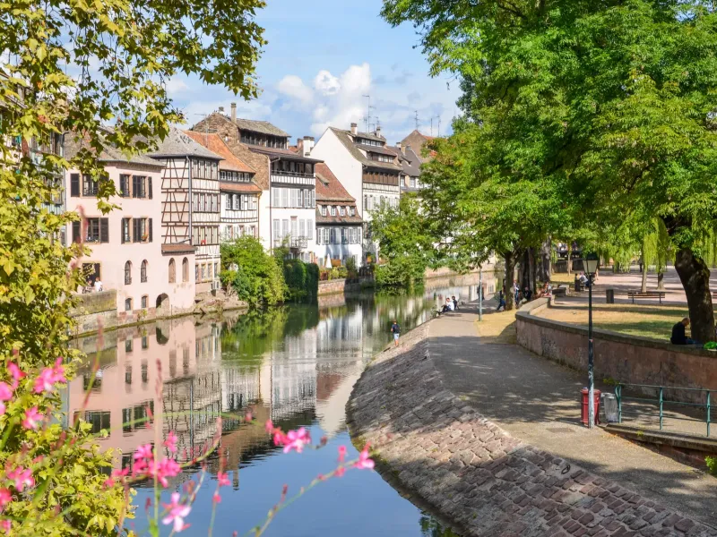 A cobbled quay beside the water in the Petite France quarter of Strasbourg, with timbered houses and window flowers.