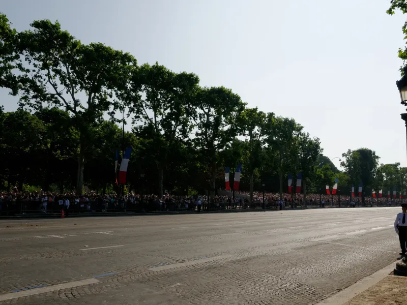 French flags hung the length of the Champs-Elysees above a crowd behind barriers on a national holiday in Paris.