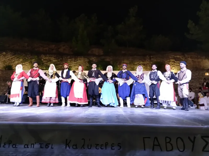 Dancers in Cretan costume holding hands in a line at an evening village festival in Crete, Greece.