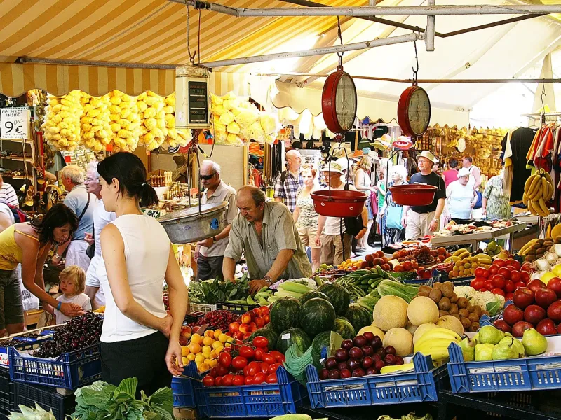 Crates of tomatoes, melons and cherries under a striped awning at the produce market in Heraklion, Crete, Greece.