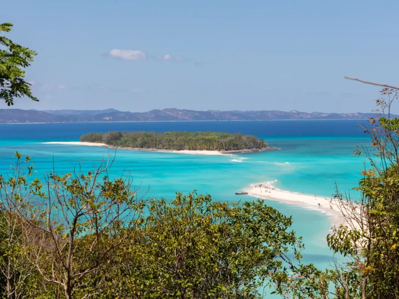 The pale sandbar joining the islets of Nosy Iranja, northwest Madagascar, seen from a wooded rise above turquoise water.
