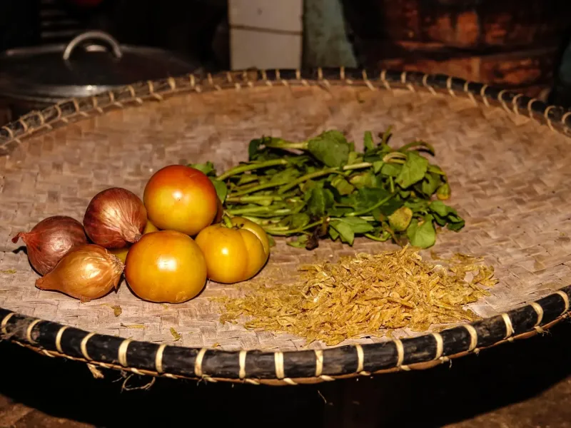 Onions, tomatoes, ginger and brede greens in a woven basket, the ingredients of romazava, the Malagasy national dish.
