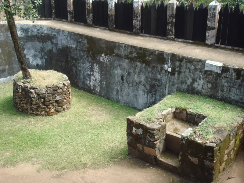 A stone enclosure and dark timber palisade inside the royal compound on the Royal Hill of Ambohimanga near Antananarivo.