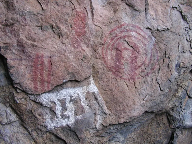 Red and white paintings on a weathered granite face in the Chongoni Rock-Art Area, Malawi, animal and geometric figures.