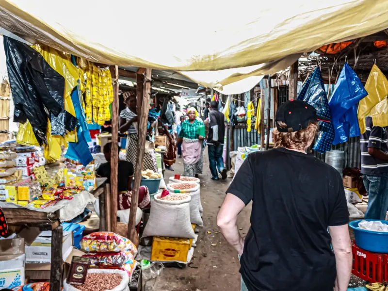 Sacks of dried beans and dried shrimp open along a covered market aisle in Vilankulo, packaged goods stacked on the stalls.