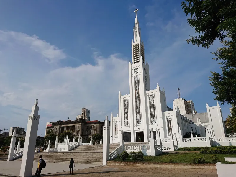 The white Art Deco cathedral in Maputo with the city hall and apartment blocks behind it under a blue sky.