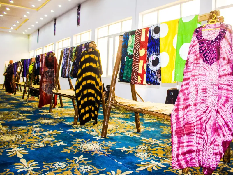 Racks of Yoruba adire resist-dyed cloth and finished garments on display at a cultural exhibition in Nigeria.