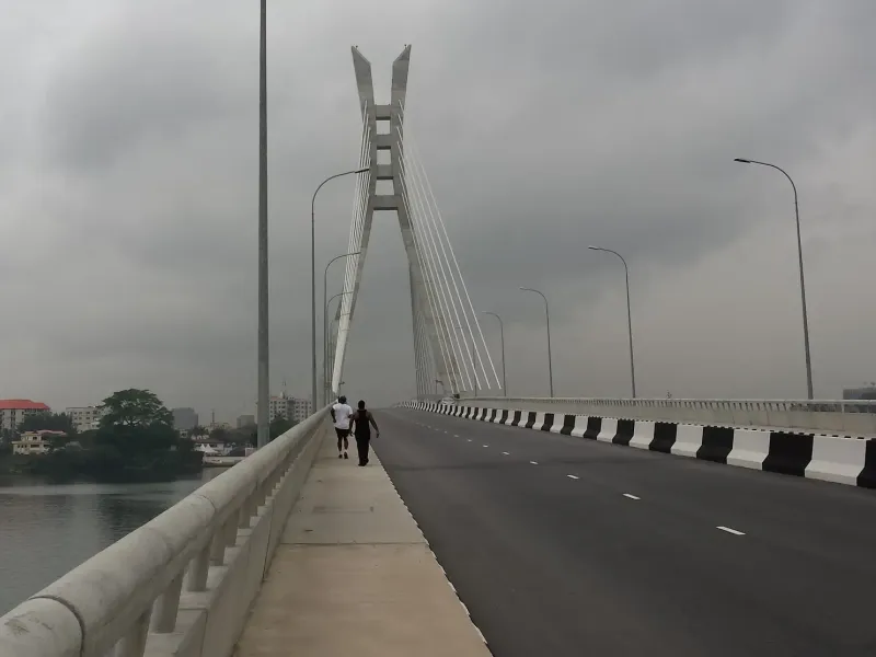 The cable-stayed Lekki Ikoyi link bridge over the lagoon in Lagos, Nigeria, with two people walking the footway.