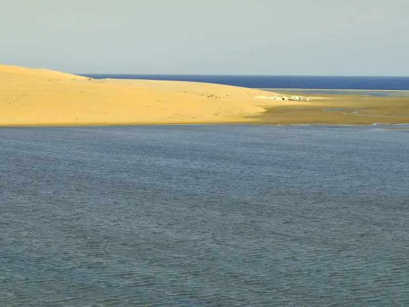 A long dune ridge meeting the still water of the inland sea in southern Qatar