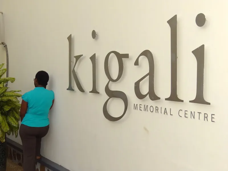 A visitor stands at the wall sign reading Kigali Memorial Centre at the genocide memorial in Kigali, Rwanda.
