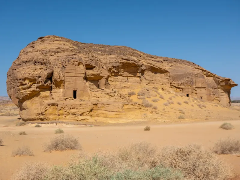 A Nabataean tomb carved into a sandstone outcrop at Hegra near AlUla, Saudi Arabia, its facade cut from the living rock.