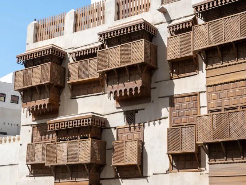 Carved wooden rawashin balconies stacked across the coral-stone facade of a merchant house in Historic Jeddah, Saudi Arabia.