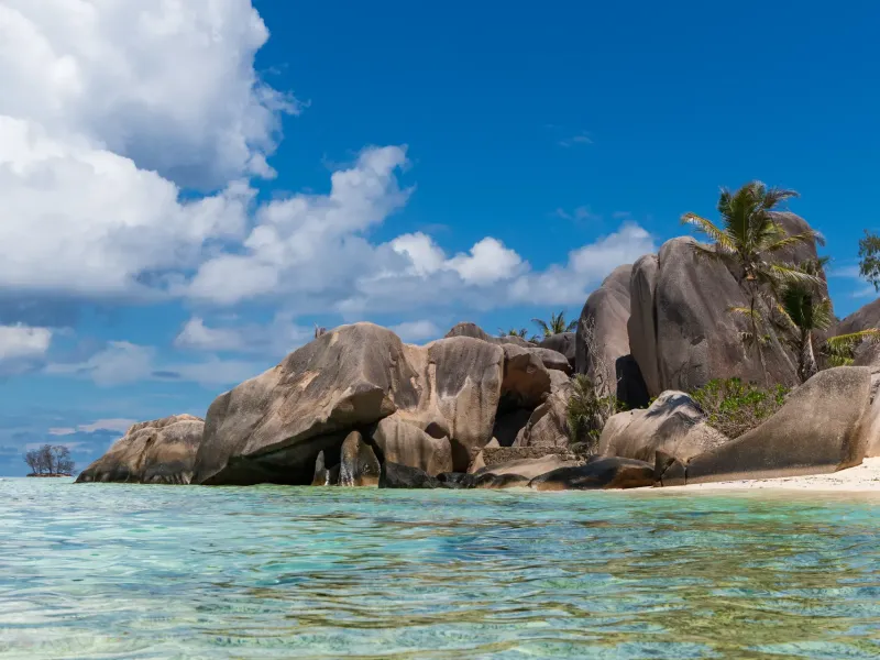 Weathered granite boulders standing in shallow turquoise water at Anse Source d'Argent on La Digue, Seychelles.