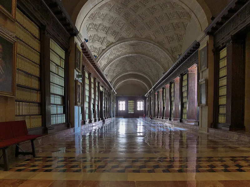 A vaulted gallery in the Archivo General de Indias in Seville, Spain, lined with cases of bound colonial records.