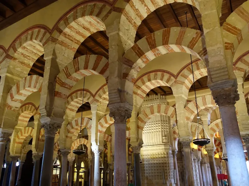 Red and cream striped double arches on marble columns in the hypostyle hall of the Mosque-Cathedral of Cordoba, Spain.