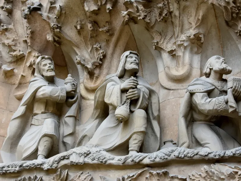 Carved stone figures of the Magi bearing gifts on the Nativity facade of the Sagrada Familia in Barcelona, Spain.