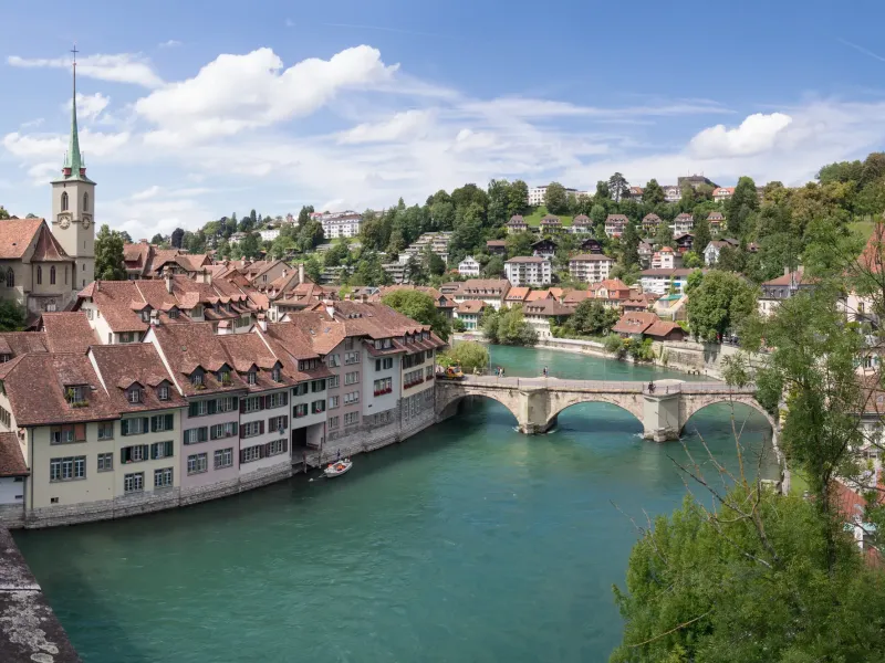 The tiled roofs of Bern's old city packed above the green Aare, with a stone bridge crossing the river below them.