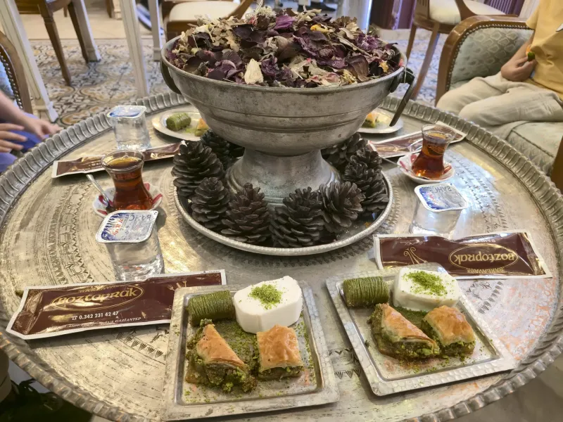 A tray of baklava in several varieties served with tulip glasses of Turkish tea.
