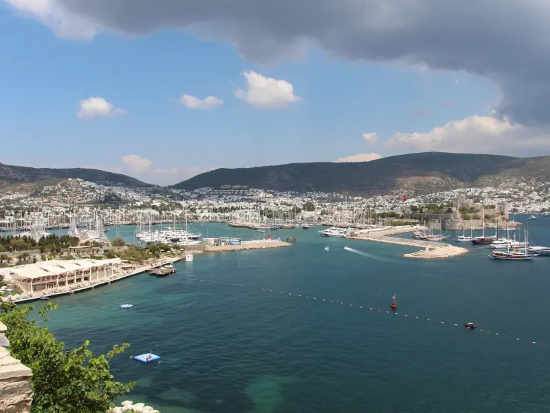 The bay and marina at Bodrum on Turkey's Aegean coast, white houses climbing the hillside above turquoise water.