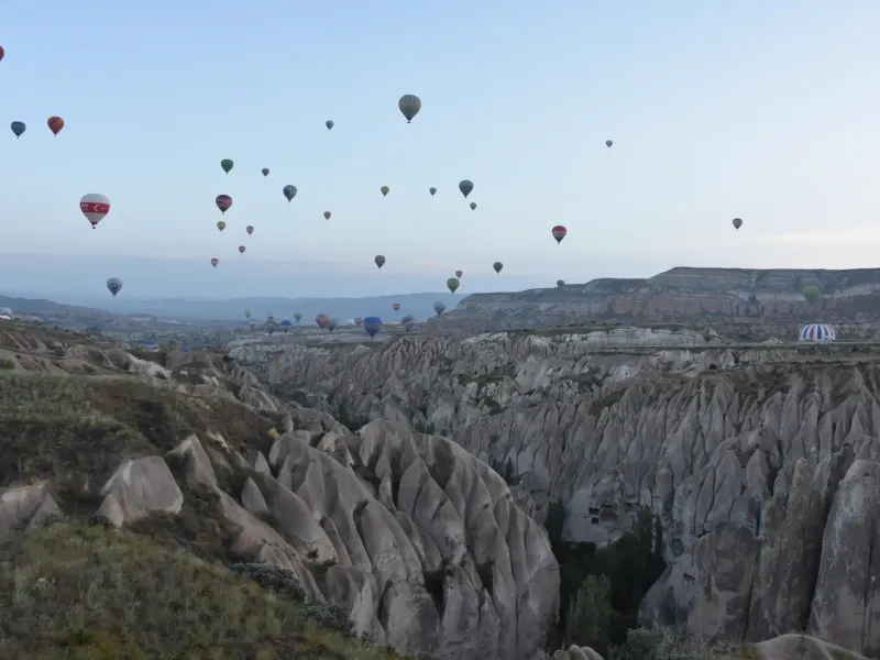 Balloons scattered above the eroded tuff valleys of Goreme National Park in Cappadocia, Turkey, at first light.