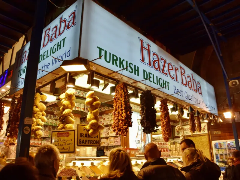 A confectionery stall hung with dried fruit and Turkish delight in the Grand Bazaar in Istanbul, shoppers at the counter.