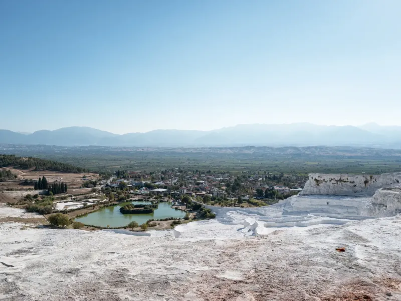 The white travertine terraces of Pamukkale in Denizli province, Turkey, stepping down towards the green valley below.
