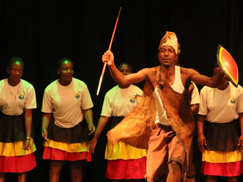 Dancers in yellow, black and red costume performing the ekitaguriro dance on a stage in Uganda.