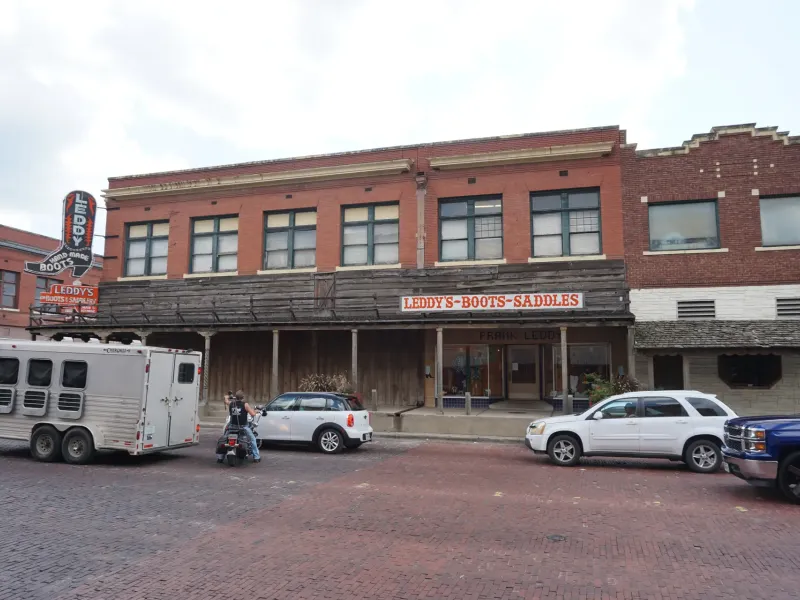 The brick storefront of Leddy's Boots and Saddles with its vintage sign on a brick street in the Fort Worth Stockyards.