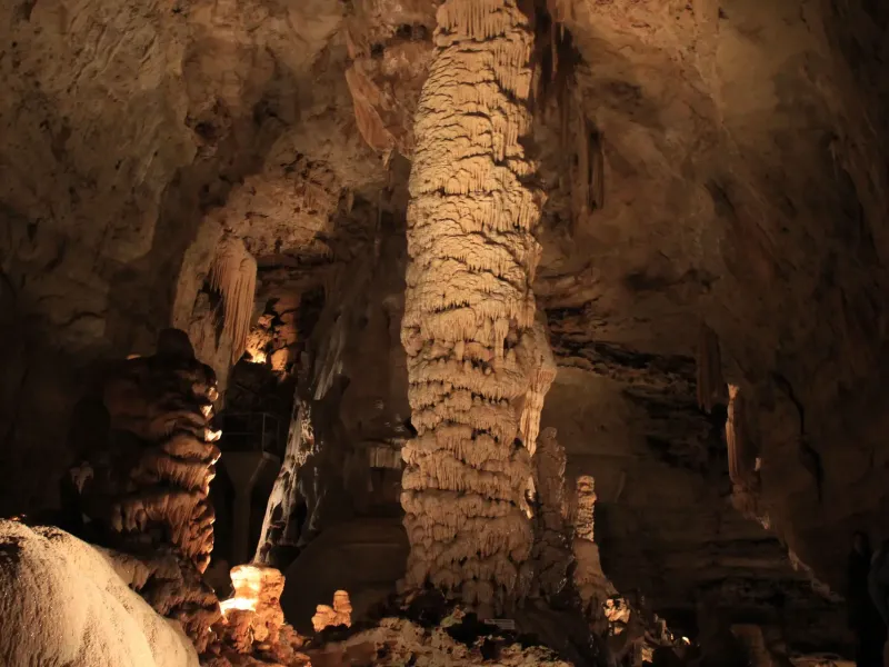 A tall limestone column and flowstone formations lit inside Natural Bridge Caverns near San Antonio.