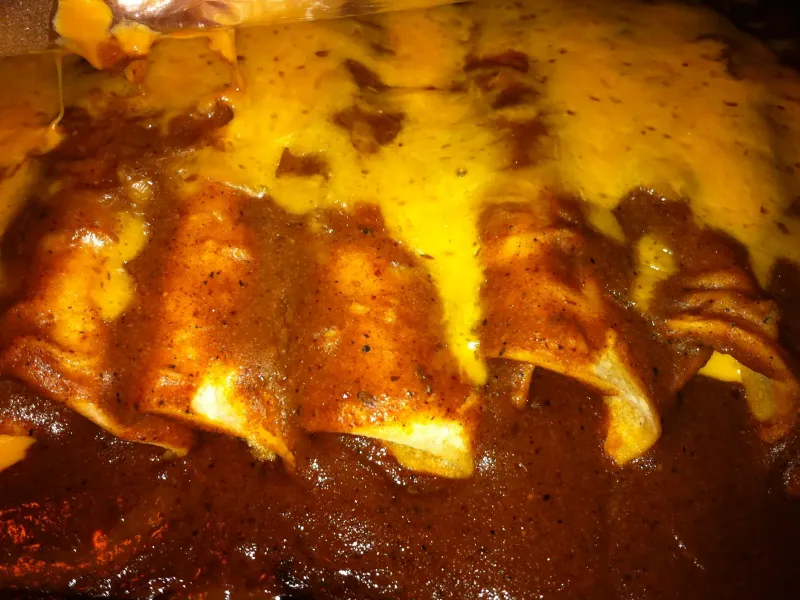 Cheese enchiladas covered in melted cheese and a rich red chili gravy, a Tex-Mex classic.