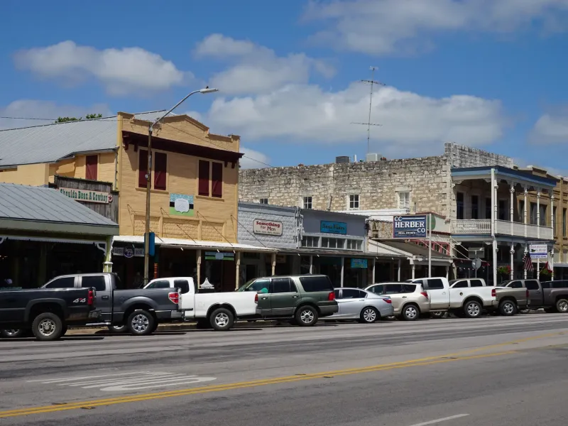 Nineteenth century limestone and painted storefronts with deep porches along Main Street in Fredericksburg, Texas.