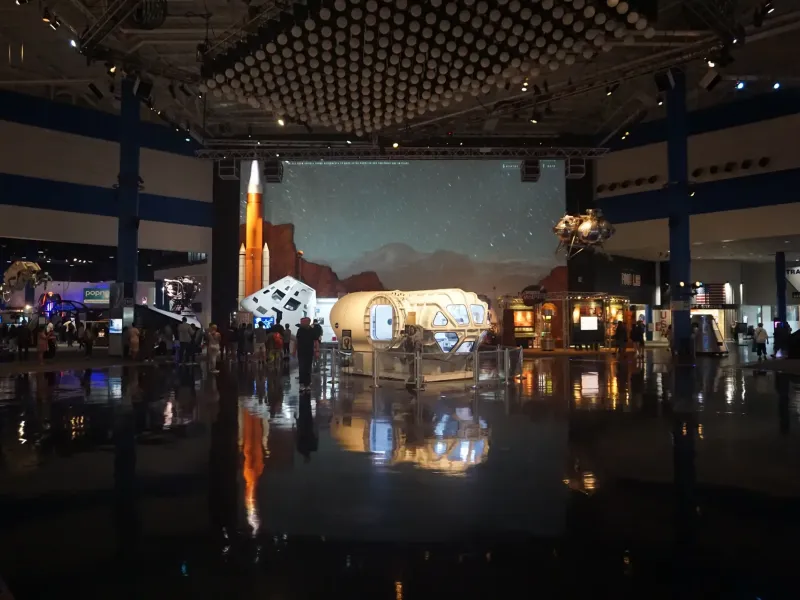 Spacecraft mockups and a rocket model glow under exhibit lights in the main hall of Space Center Houston.