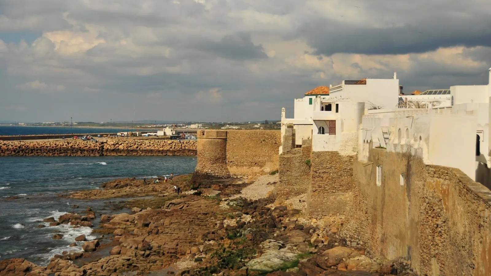 A whitewashed Moroccan town on ochre ramparts above a rocky Atlantic shoreline.