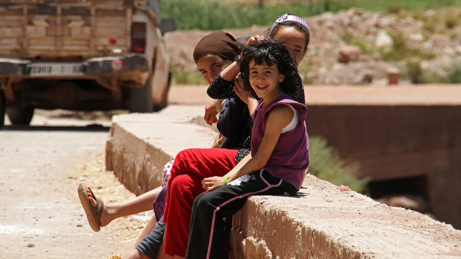 Three smiling Moroccan children sitting