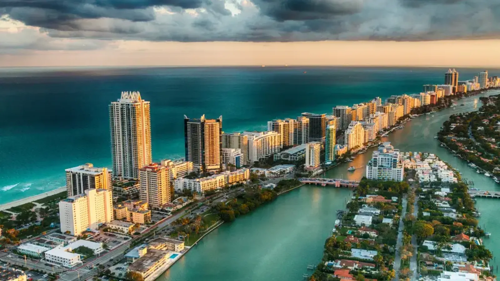 Aerial sunset view of Miami Florida's South Beach skyline with turquoise Atlantic Ocean and Intracoastal Waterway below stretching to the horizon
