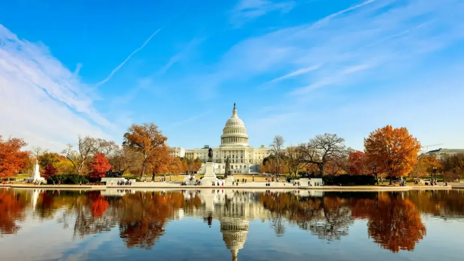 US Capitol building reflected in the Capitol Reflecting Pool surrounded by autumn foliage in Washington; DC on a clear day.